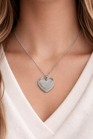 Dubbelt hjärthalsband med silverglitter buren på person i dagsljus