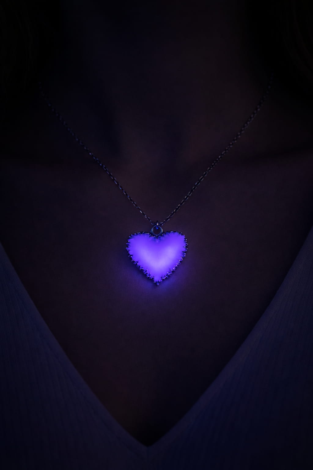 Frostigt hjärta halsband buret på person med lila sken i mörker