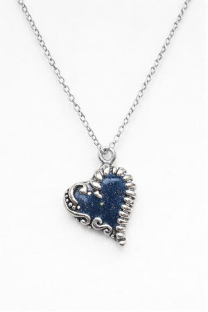 Antikt silverhalsband med mörkblått hjärta och guldkorn i dagsljus