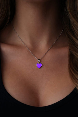 Rosa hjärthalsband som lyser lila på person