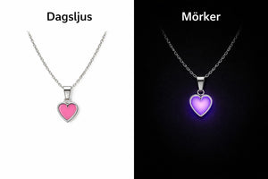 Silverhalsband med rosa hjärta i dagsljus och i mörker