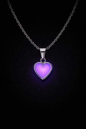 Silverhalsband med rosa hjärta som lyser lila i mörker