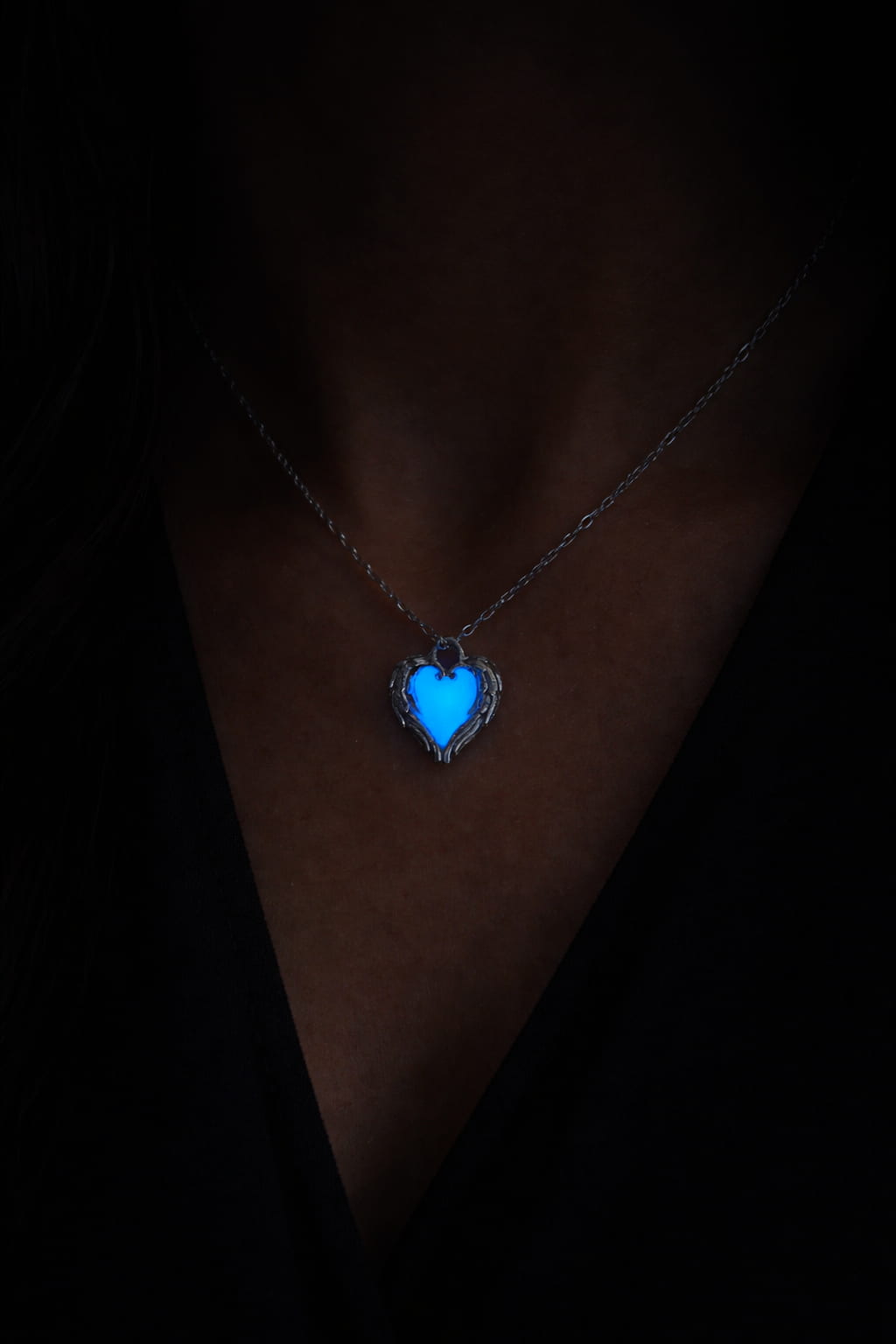Självlysande hjärthalsband med blått sken buren på person i mörker