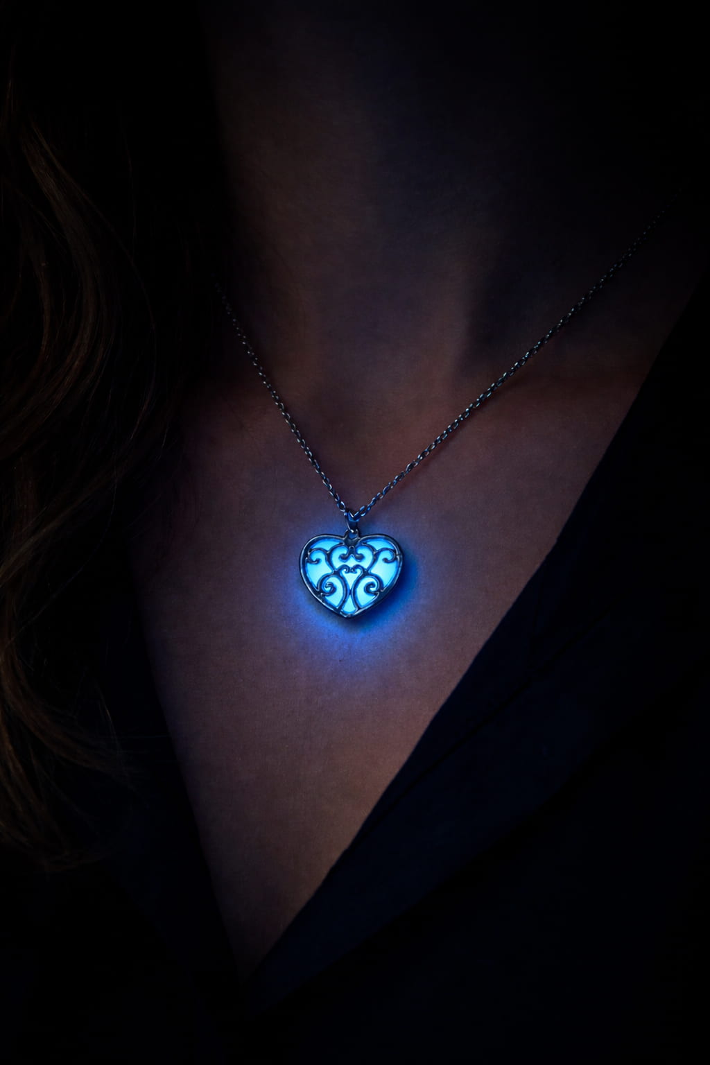 Självlysande hjärthalsband med blått sken buren på person