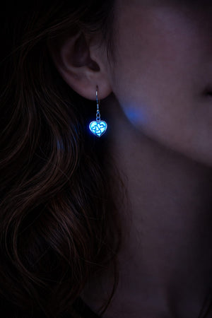 Små självlysande hjärtörhängen med blått sken buren på person i mörker