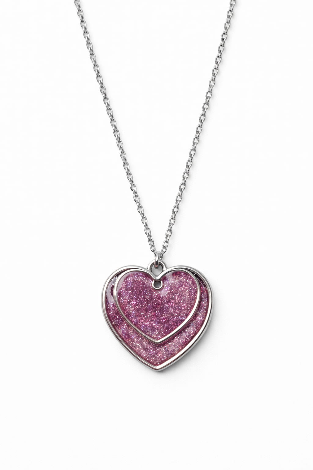 Dubbelt hjärthalsband med rosa glitter på vit bakgrund i dagsljus