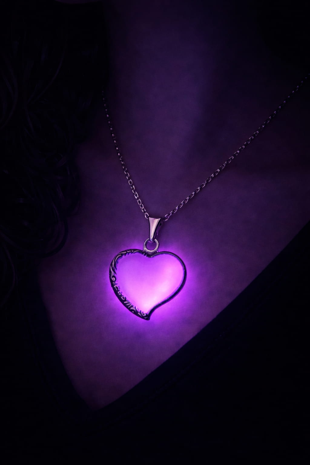 Halsband med rosa hjärta, lila sken buren på person i mörker