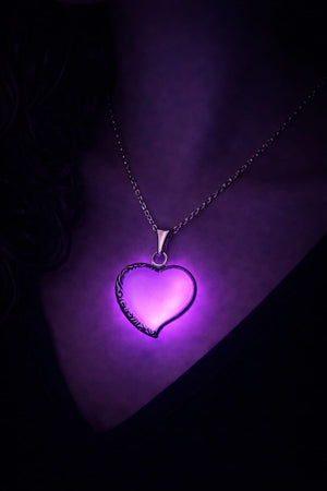 Halsband med rosa hjärta, lila sken buren på person i mörker