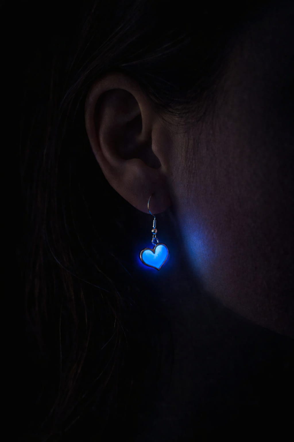 Hjärtörhängen med blått sken buren på person i mörker