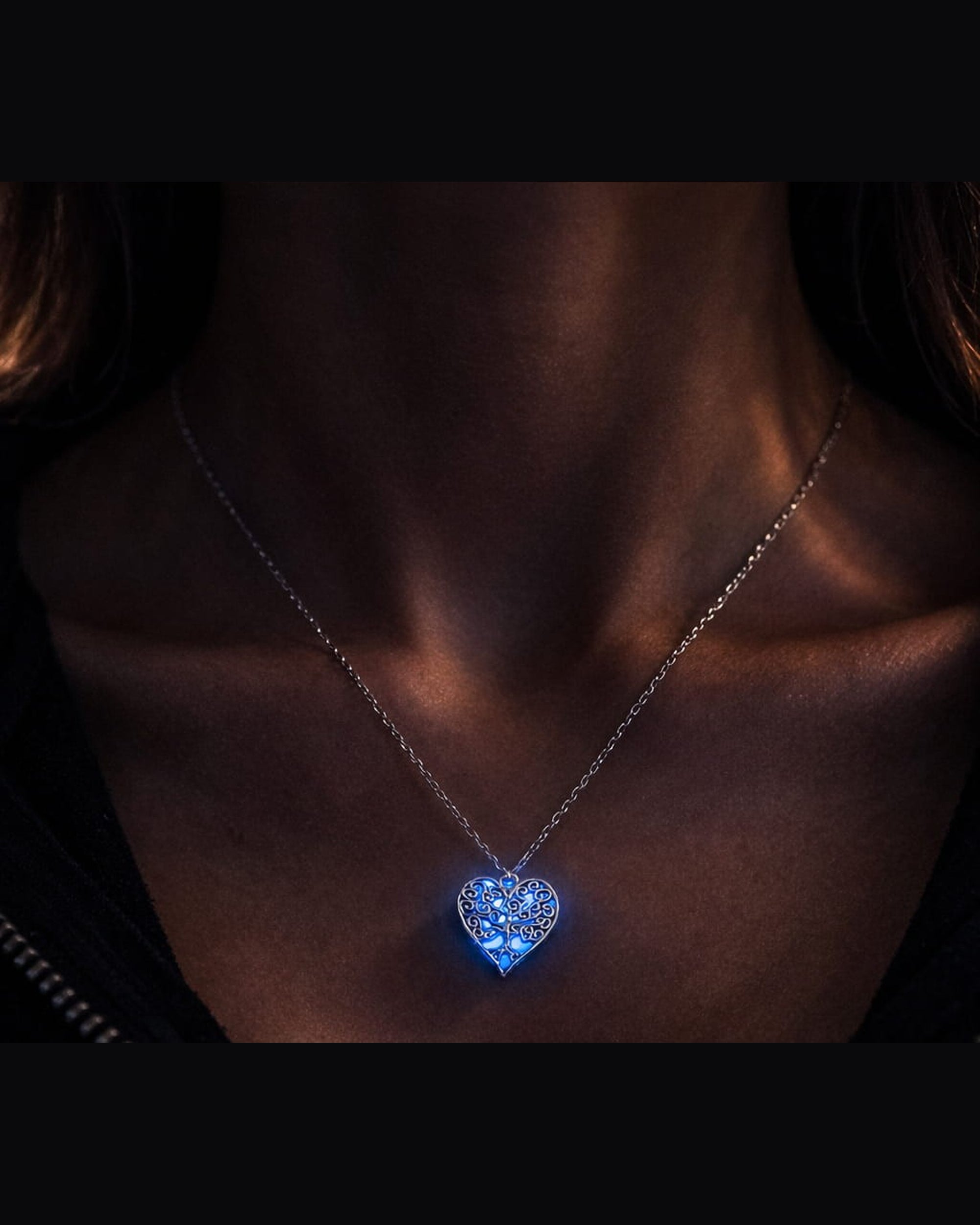 Livets träd i hjärtform med blå lyster buren på person i mörker