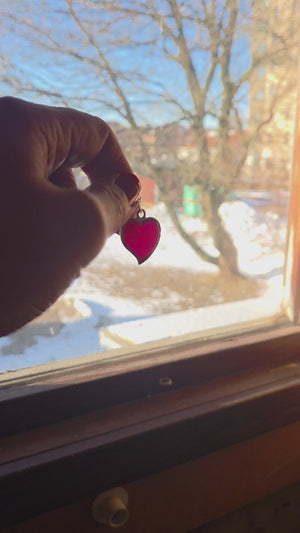 Video som visar rosa hjärtfavorit halsband laddas i dagsljus och ger lila sken i mörker