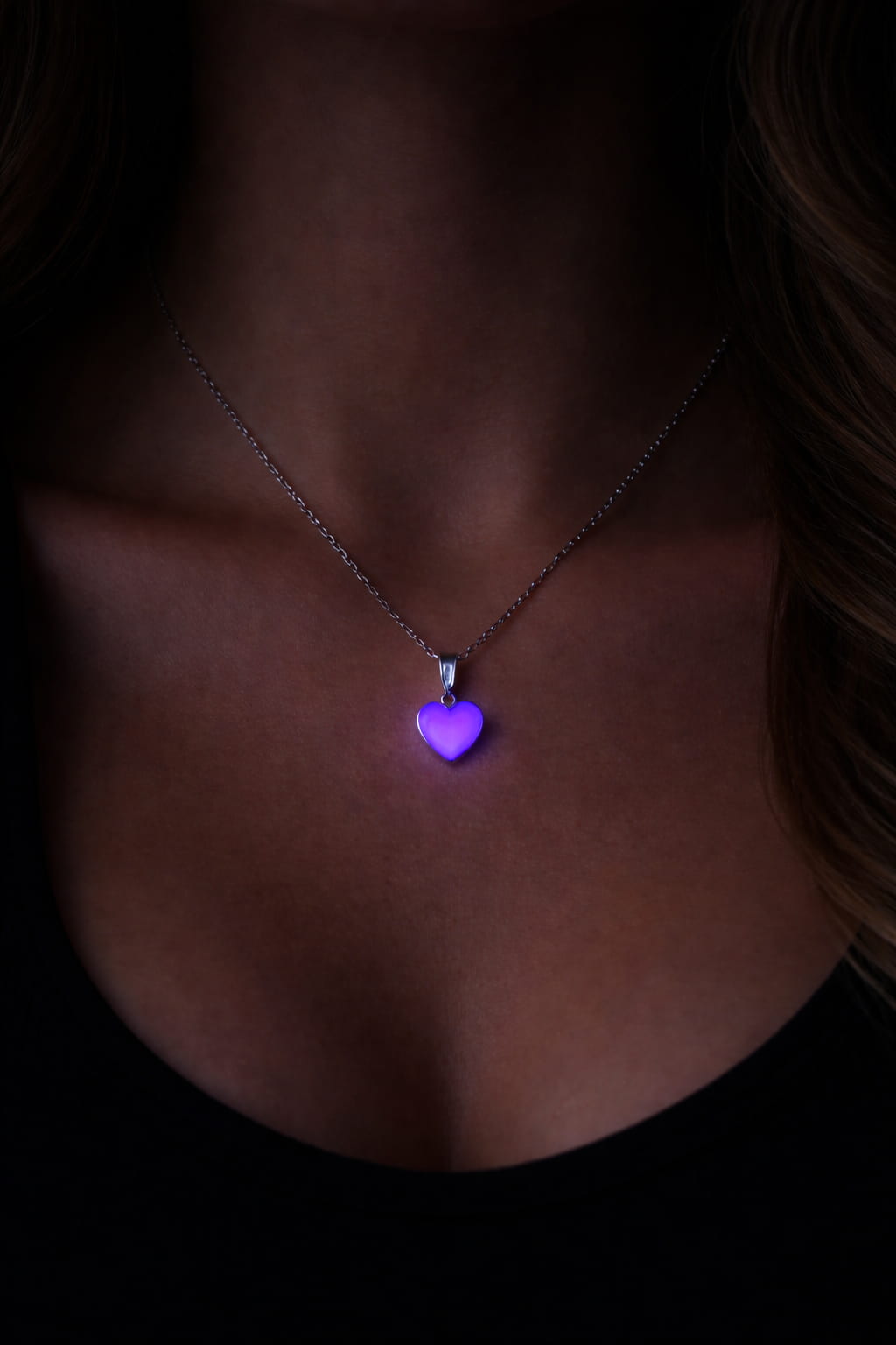 Rosa hjärthalsband på person som lyser lila i mörker