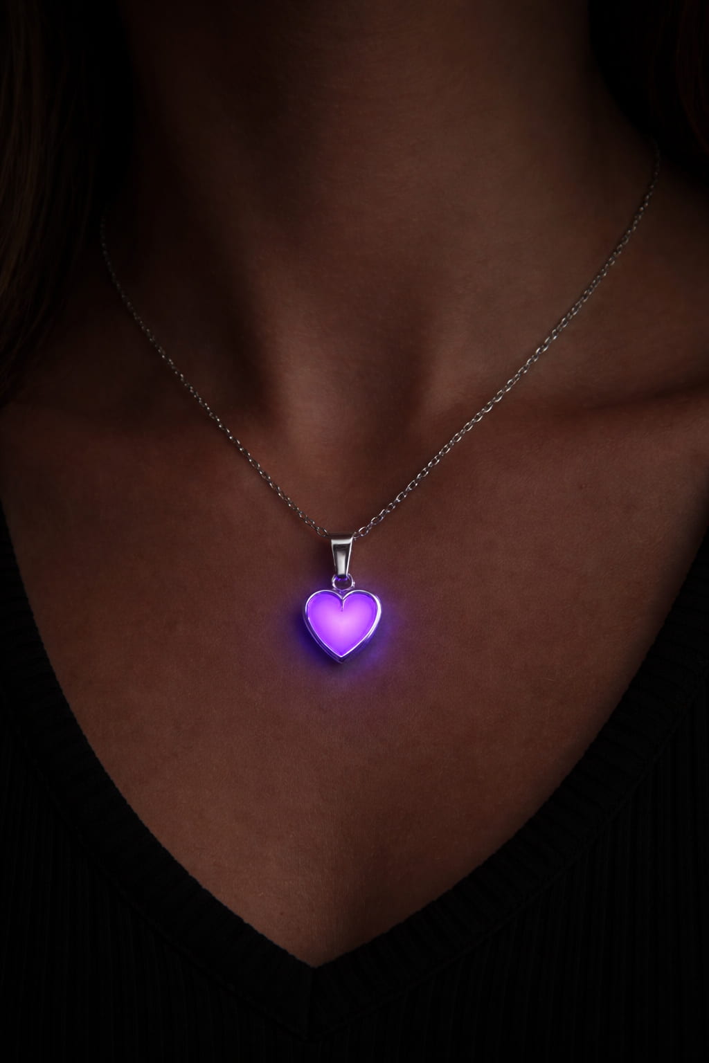 Silverhalsband med rosa hjärta som lyser i mörker på person